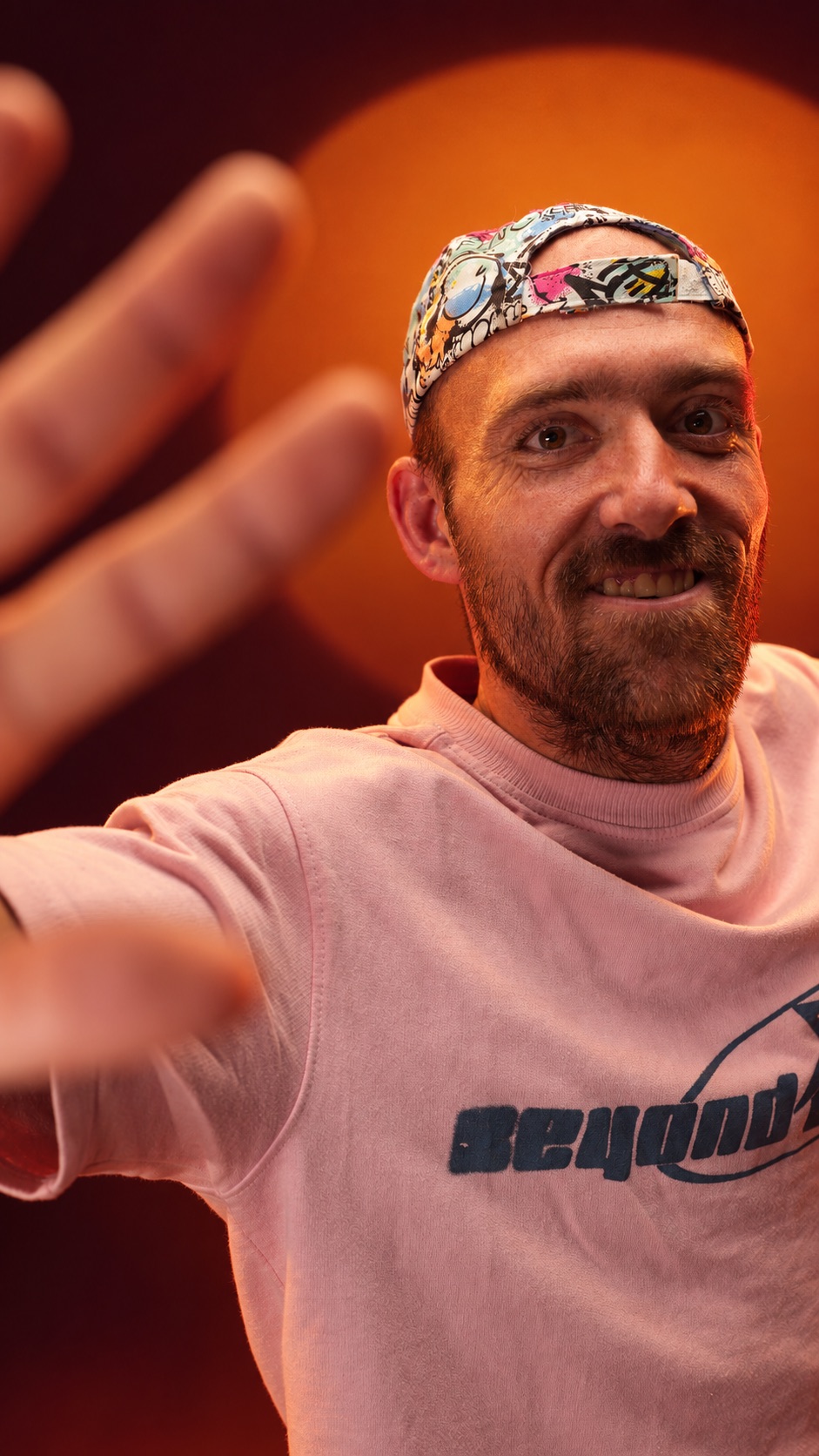 Nabyskoot van Marius wat sy hand na die kamera uitsteek, amber agtergrond
